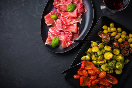 Assortment of appetizers and tapas with red wine on black backgroundの写真素材