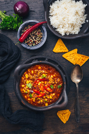 Bowl of chili con carne with rice and toppings on wooden tableの写真素材