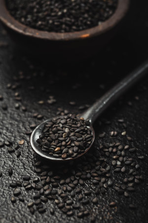 Black sesame seeds in small bowl on black backgroundの写真素材