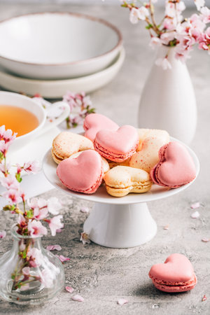 Macarons or French macaroons in heart shapes with cherry blossom branch for Mothers Dayの写真素材