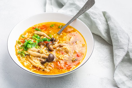 Tomato egg drop soup  with mushrooms in a white bowl. Traditional Chinese food, Asian cuisineの写真素材