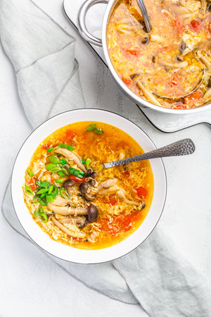 Tomato egg drop soup  with mushrooms in a white bowl. Traditional Chinese food, Asian cuisineの写真素材
