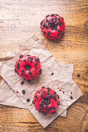 Puff pastry donuts with pink icing and cookie chips on baking paperの写真素材