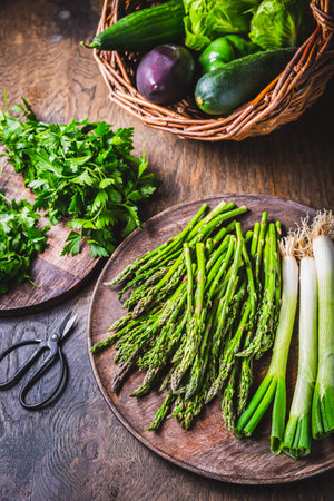 Fresh green asparagus with green onion and herbs on wooden tableの写真素材