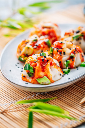 Steamed dumplings Dim Sum with  hot Sriracha sauce and green onions and sesame seeds.の写真素材