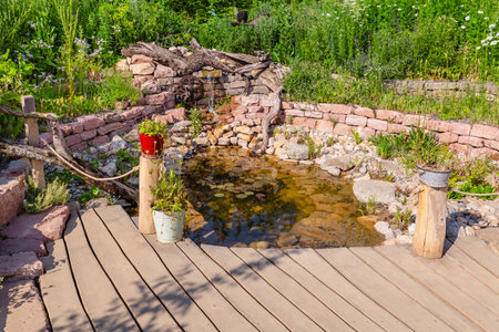 Natural garden with small patio, native plants, natural stones, pond and potted plantsの写真素材