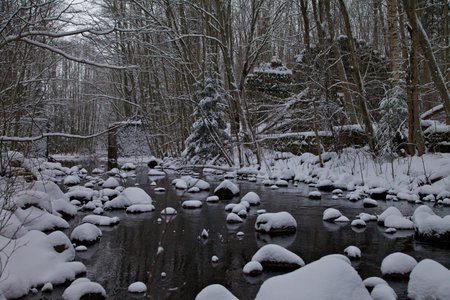 Brook with snow covered stonesの写真素材