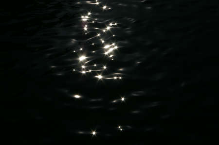 Sunlight sparkles on the dark sea wavesの写真素材