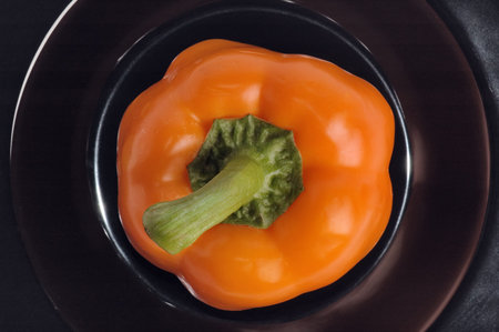 Orange sweet pepper on a black plate