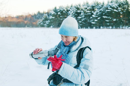 The woman pours from a thermos tea, in winter on walk