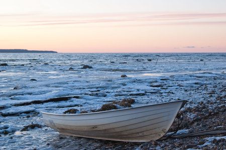 Fishing boat on the bank of the frozen seaの写真素材