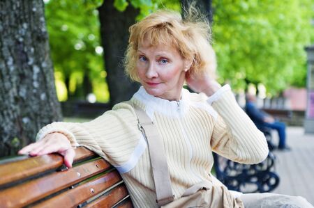 a middle-aged woman sits on a park benchの写真素材