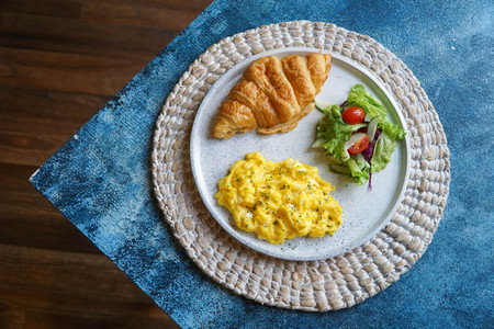 Breakfast with croissant, scrambled egg, and vegetables salad in the morningの写真素材