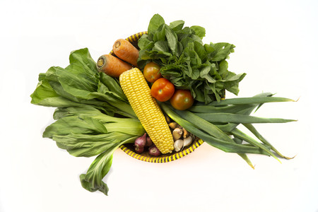 Top view of various fresh vegetables in a bamboo basket isolated on whiteの写真素材