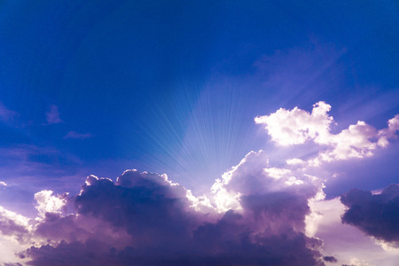 Beautiful blue sky with sunrays rising from behind clouds with copy spaceの写真素材
