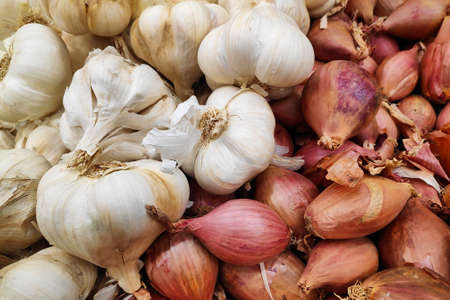 Stack of garlics and shallots on a market stall.の写真素材