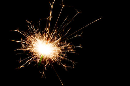 Close-up on a sparkler lit in the dark with copy space on the right.の写真素材
