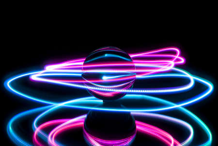 Circular light painting around a glass ball on a black backgtound with reflection.の写真素材