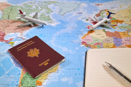 Travel planning concept composed of a world map with on it, two toy planes, a French passport and a...