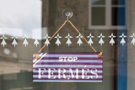 Sign hanging at the glass door of a shop saying in French (Stop, nous sommes fermÃ©s), meaning in English (Stop, we are closed).の写真素材