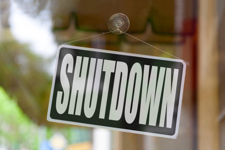 Close-up on a red open sign in the window of a shop displaying the message: Shutdown.の写真素材