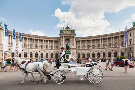 Vienna, Austria - June 17 2018: Carriage passing in front of the Austrian National Library located in the Neue Burg Wing of the Hofburg in center of Vienna.のeditorial素材