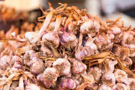 Close-up on a stack of garlics on a market stall.