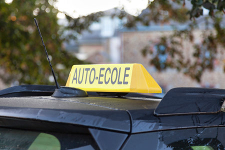 Yellow car roof sign with written in it in French Auto-Ã‰cole, meaning in English Driving school.