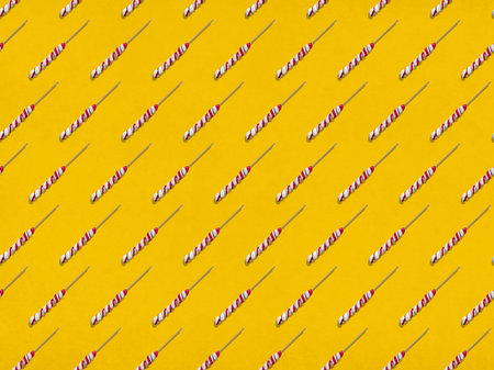 Many sweet lollipops arranged in rows on yellow background