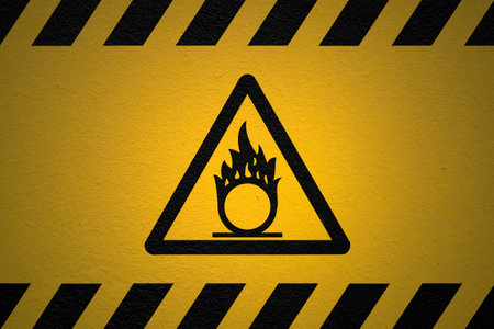 Black striped yellow background with a Self ignition warning sign and a light effect to dramatize the whole.の写真素材