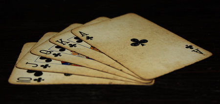 Studio shot of a royal flush of clubs on a black background.