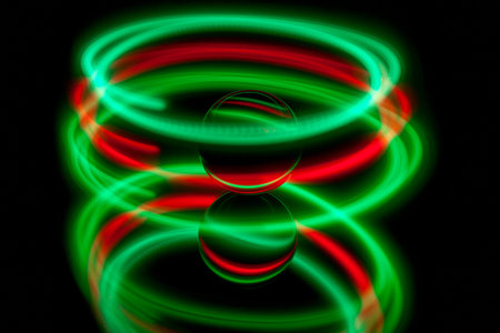 Abstract light painting circling around a glass ball on a black backgtound.