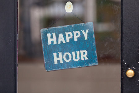 Sign attached to a glass door saying âHappy Hourâ.の写真素材