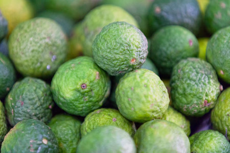 Full frame close up on a stack of kaffir limes (Citrus hystrix) on a market stall.