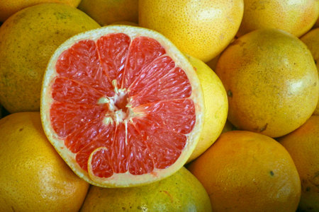 Close-up on a stack of Grapefruits on a market stall with one cut in half.の写真素材
