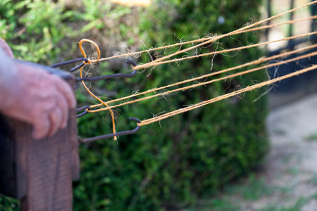 Close-up on the hands of a medieval rope weaver weaving a rope.