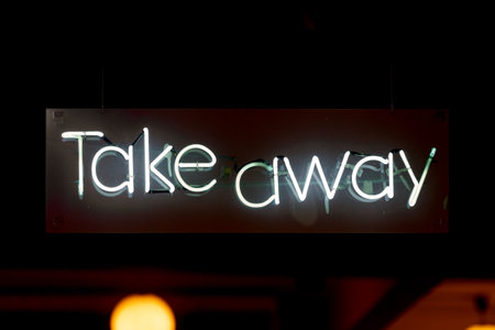 Close-up on a white neon light shaped into the word "Take away".の写真素材