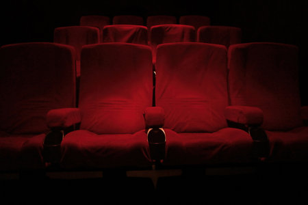 Rows of red velvet seats in a dark and totally empty.の写真素材