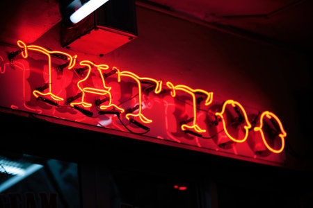 Close-up on a red neon light shaped into the word Tattoo.