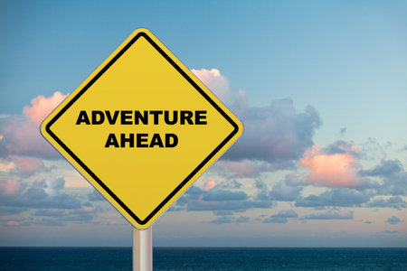 Diamond-shaped crossing sign with yellow background and black border with a short phrase saying âAdventure Aheadâ in the middle.の写真素材