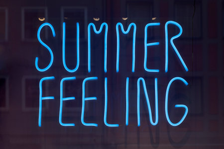 Blue neon in the window of a bar saying "Summer feeling".の写真素材