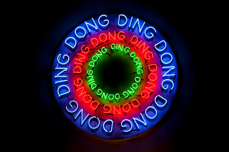Close-up on a colorful circular sign composed of colorful neon light shaped into the words "Ding dong".の写真素材