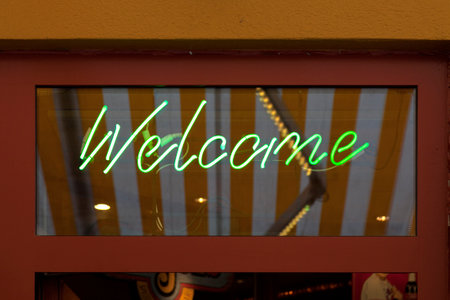 Close-up on a green neon light shaped into the word "Welcome".の写真素材
