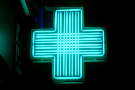 Close-up on a green neon light shaped in a cross used to show a pharmacy.の写真素材