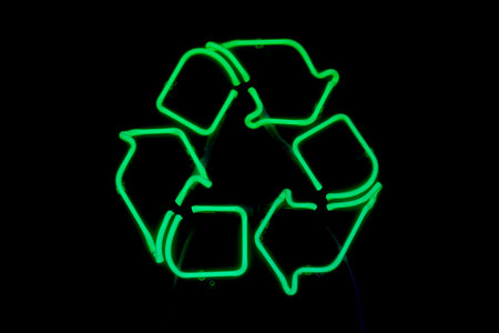 Green neon light shaped into a recycling symbol.の写真素材