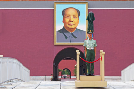 Beijing, China - August 08 2018: Guard with behind the portrait of Mao at the entrance of the Forbidden City.のeditorial素材