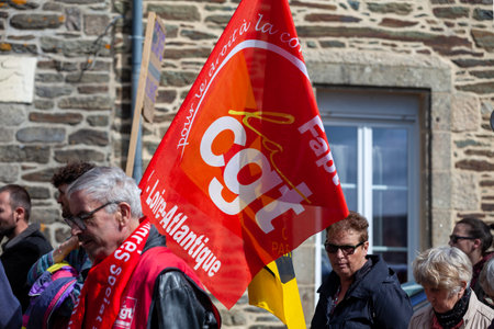 Carhaix, France - May 1 2023: Demonstration against the pension reform with a demonstrator waving a CGT flag, a national trade union center.のeditorial素材