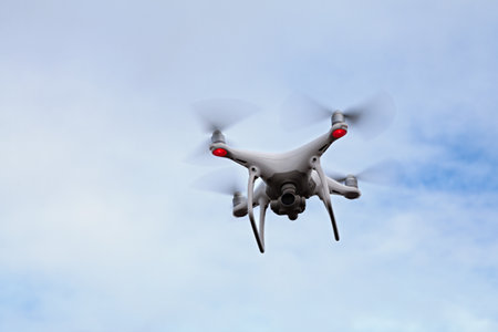 Close-up on a white drone hovering in a cloudy sky.の写真素材