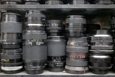 Stack of camera lenses and doubleurs on a shelf.の写真素材