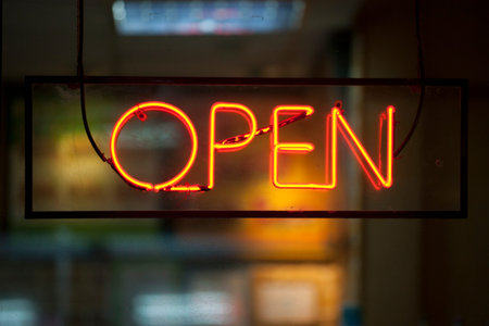 Close-up on a neon light shaped into the word Open.
